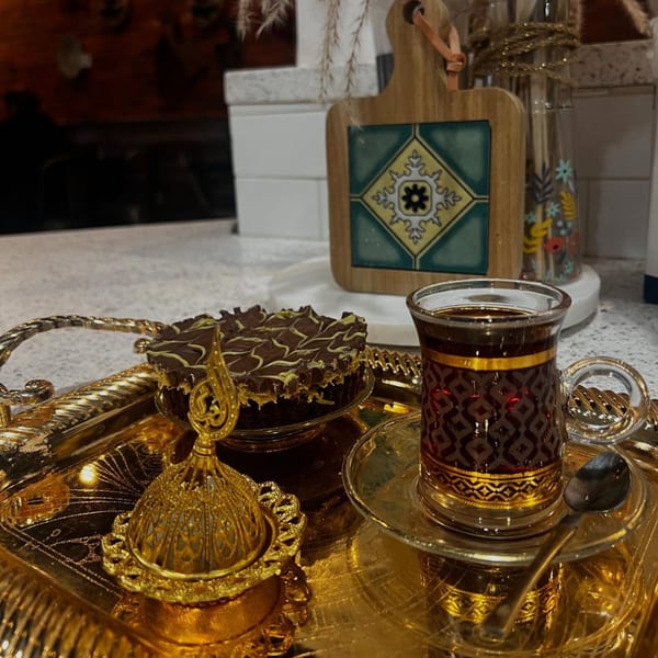 Middle-Eastern tea and chocolate cake on a golden tray with decorative elements.