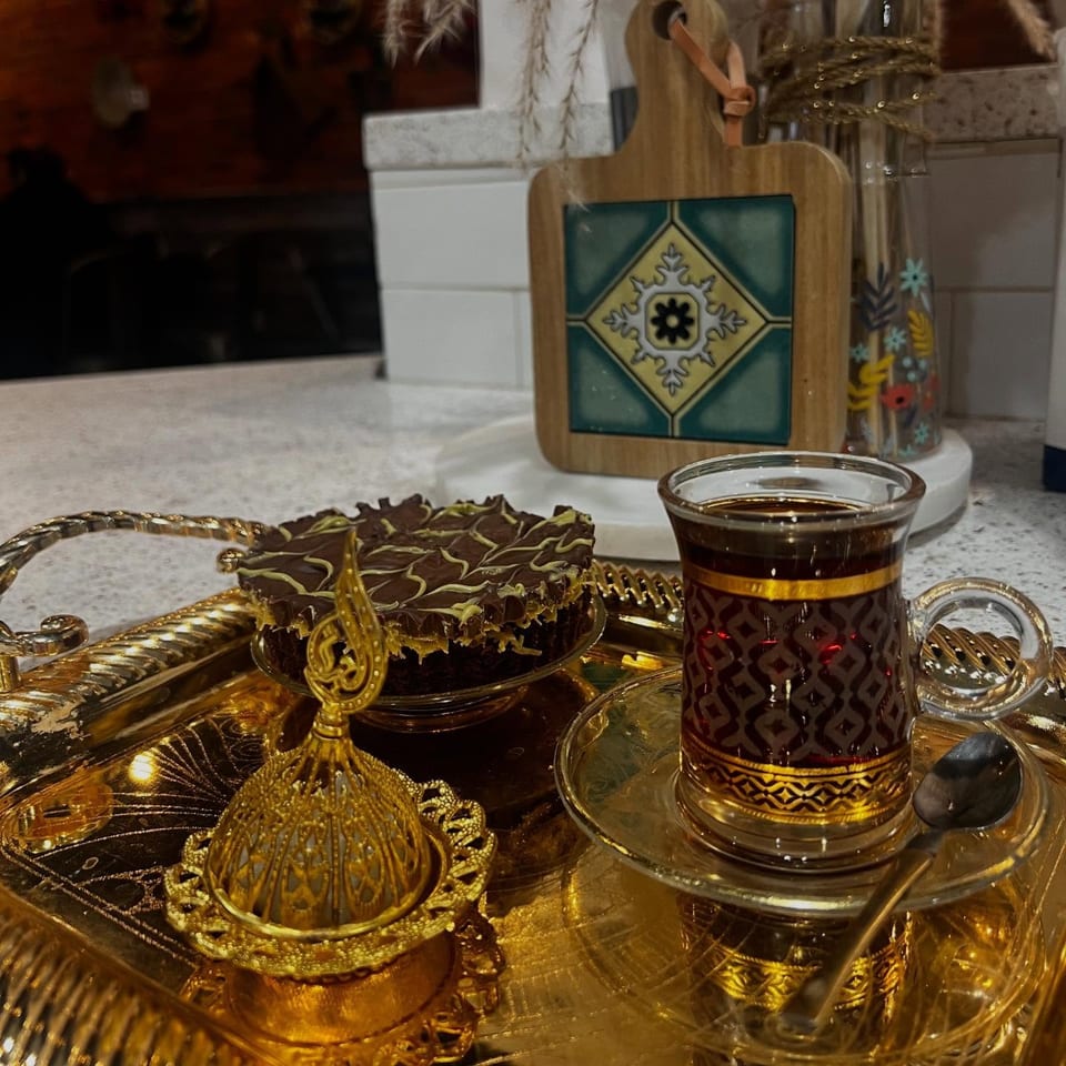 Middle-Eastern tea and chocolate cake on a golden tray with decorative elements.