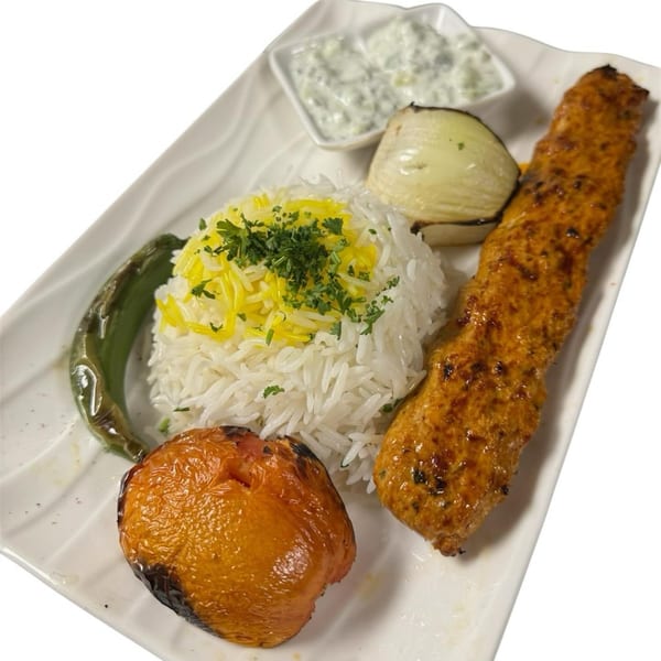 Middle-Eastern chicken kebab with rice, grilled vegetables, and a side of yogurt sauce.